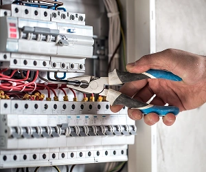 Electrician Using Pliers On Circuit Breaker Panel At Southwest Florida
